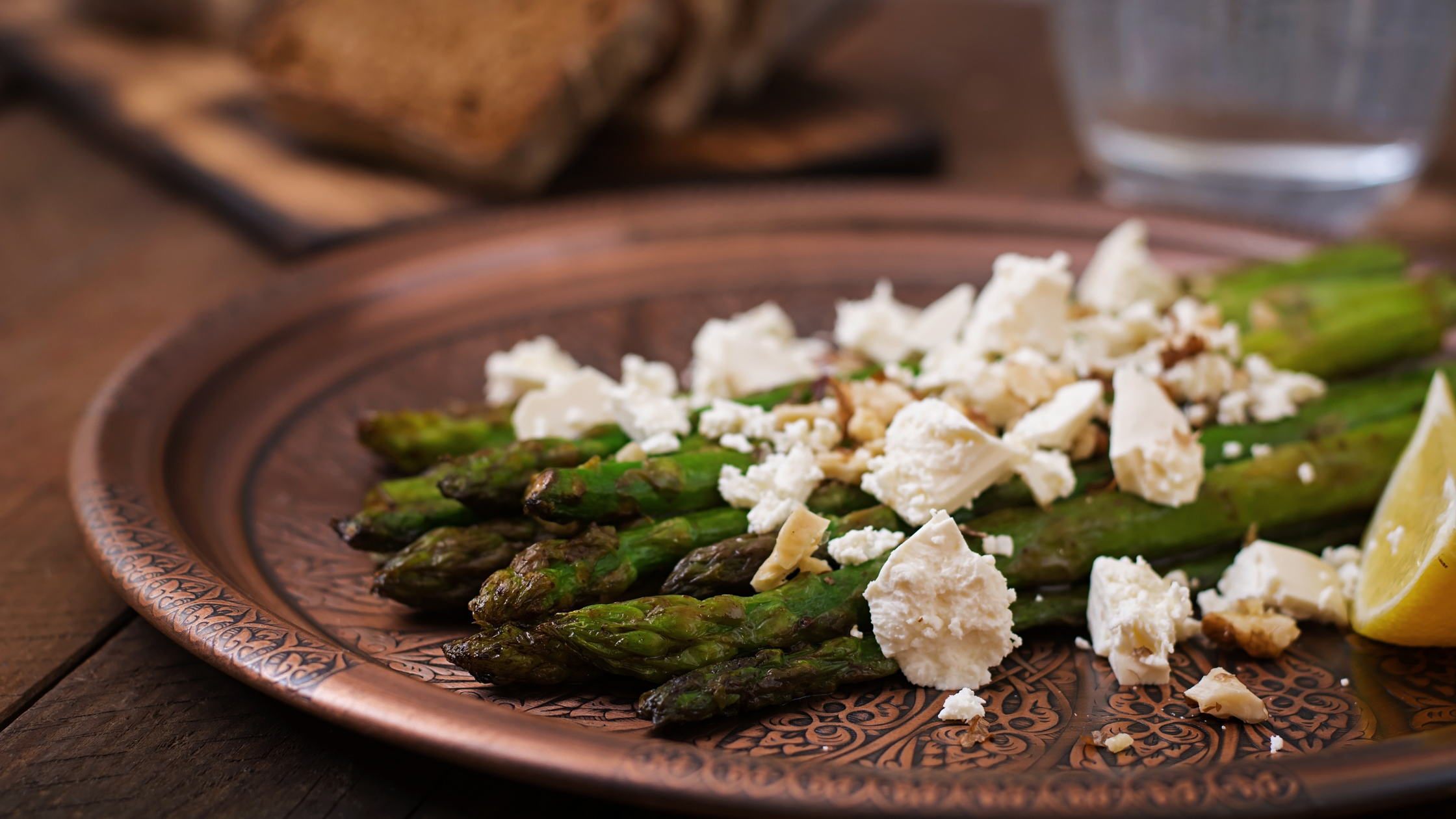 Brown gold plate of barbecued asparagus with feta and lemon